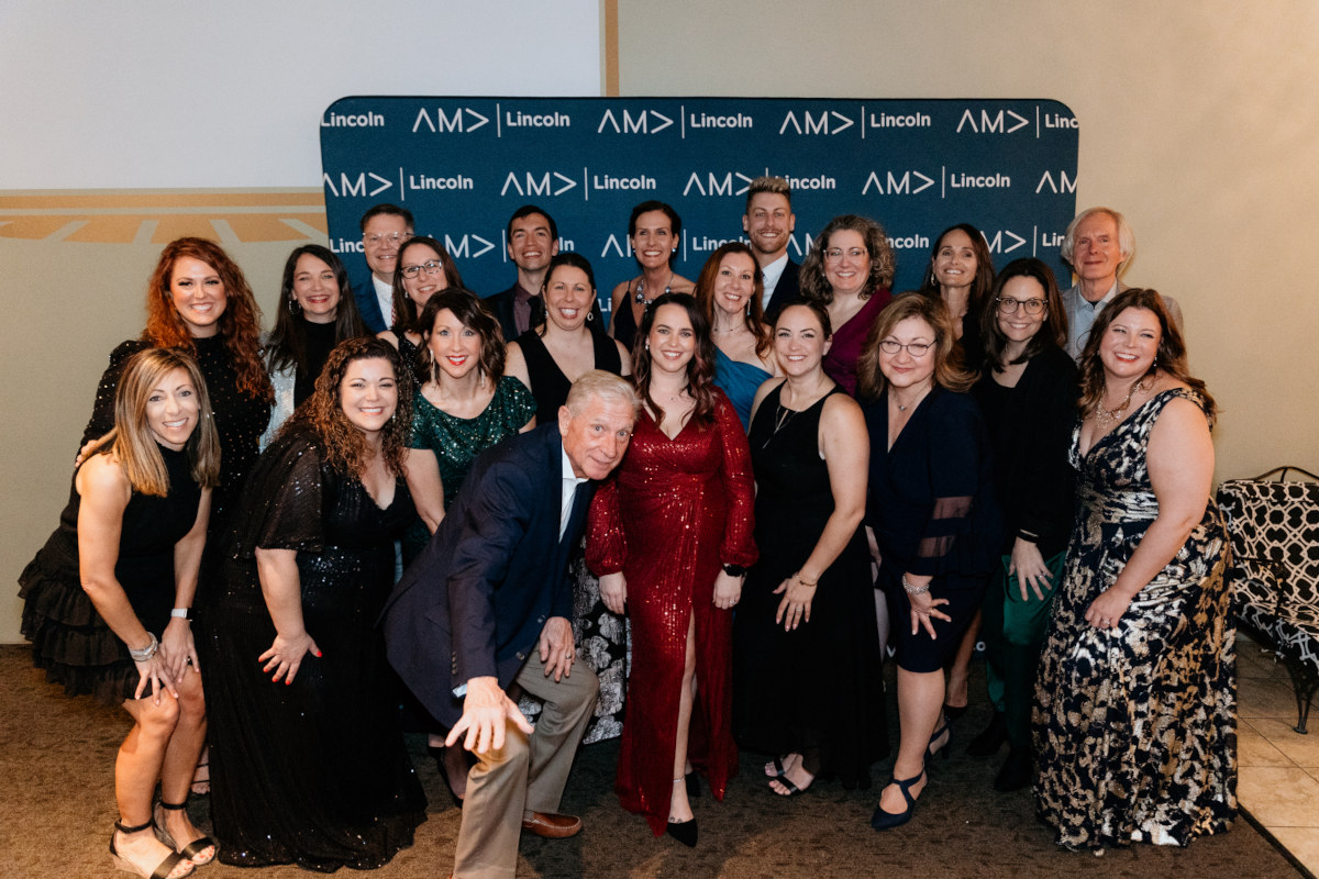 Group of past AMA presidents posing in front of branded AMA Lincoln backdrop